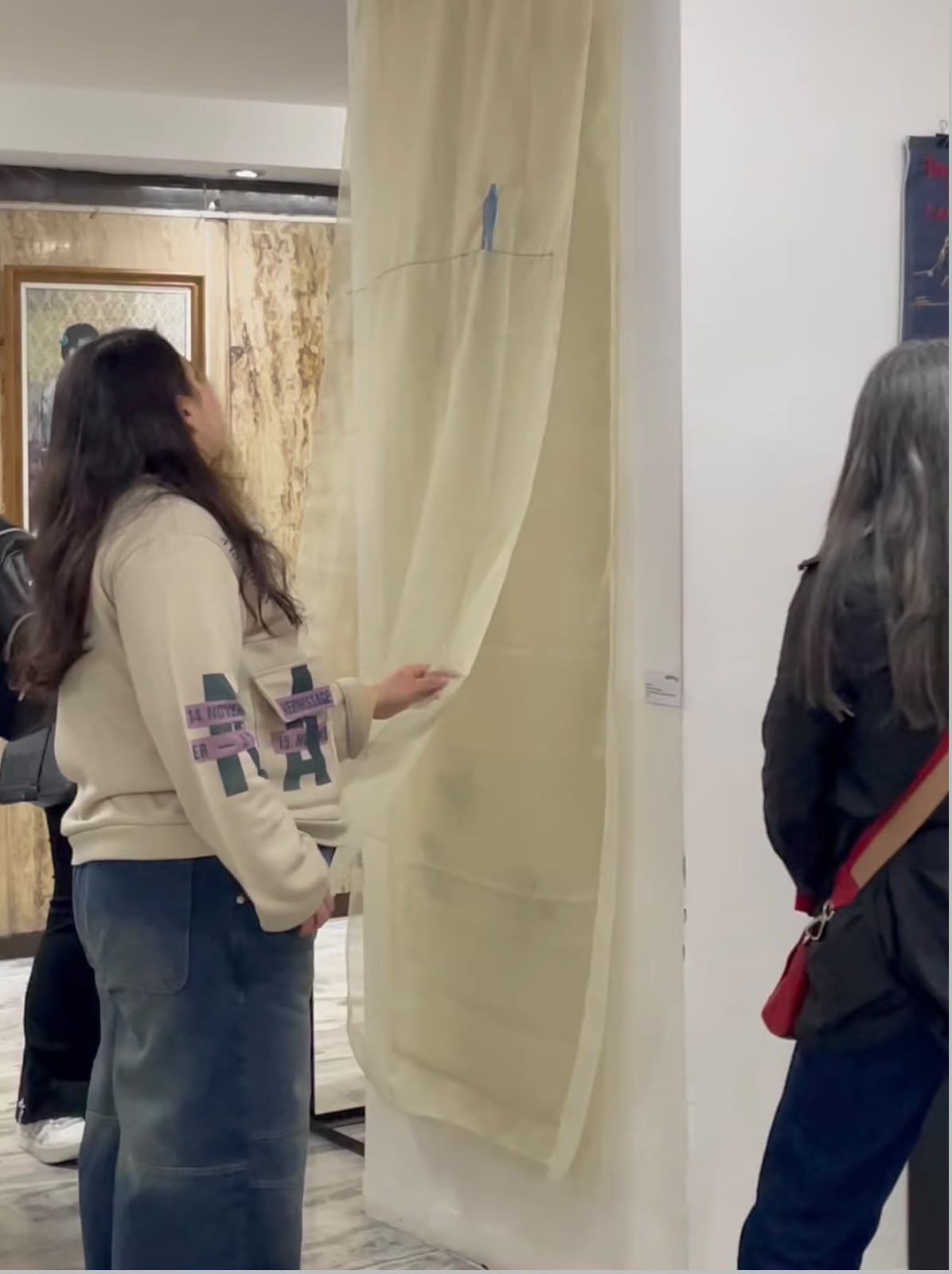 Visitantes frente a la obra textil, una de ellas tocando la tela